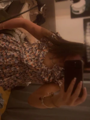 fest topp - Supersöt blommig blus med volanger och v-ringning. Toppen är ärmlös och har en luftig passform med flera lager volang. Perfekt för dig som gillar färgglada och romantiska plagg.