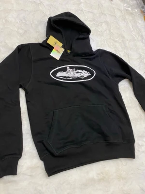 Svart loungewear set med tryck - Svart loungewear set med hoodie och byxor, båda med vitt tryck av ett skepp på bröstet och benet. Hoodien har känguruficka och byxorna har resår i midjan. Perfekt för chill dagar hemma eller när du vill vara bekväm men ändå snygg.