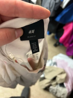 Vit relaxed fit t-shirt från H&M - Vit t-shirt från H&M i relaxed fit med tryck av en röd ros och text på bröstet. Klassisk rund halsringning och korta ärmar. Tillverkad i mjuk bomull, perfekt för en avslappnad stil.