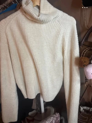 Beige polotröja i ribbstickat - Mysig beige polotröja i ribbstickat material med långa ärmar och avslappnad passform. Perfekt för lager på lager och enkel att styla till olika outfits. Polokragen ger extra värme och trendig look.