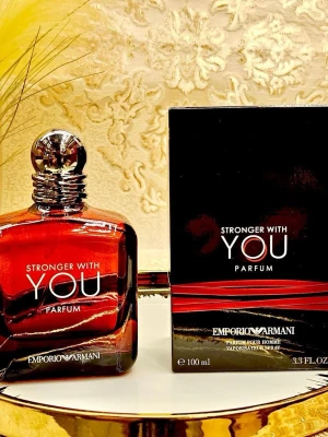 Emporio Armani Stronger With You Parfum - Emporio Armani Stronger With You Parfum är en elegant herrdoft i en lyxig, mörkröd glasflaska med silverfärgad kork. Flaskan rymmer 100 ml och har en modern, stilren design. Parfymen levereras i en svart kartong med röda detaljer och tydlig logotyp.