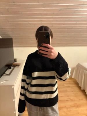 Svartvit randig stickad tröja - Säljer en oversized stickad tröja med breda svarta och vita ränder. Tröjan har rund halsringning, långa ärmar och ribbade muddar. Perfekt för dig som gillar en avslappnad och trendig stil. 
