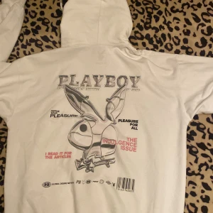 Vit hoodie från Playboy - Säljer en vit hoodie från Playboy med tryck på baksidan. Hoodien har en stor Playboy-logga och text i olika färger. Den har en klassisk passform med långa ärmar och en rymlig ficka framtill. Står storlek M men skulle snarare säga L-XL, jag har normalt sett S. 
