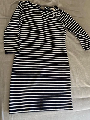 Randig klänning från Springfield - Snygg randig klänning från Springfield i marinblått och vitt. Modellen är en kortklänning med trekvartsärm och rund hals. Tillverkad i mjuk bomull som känns skön mot huden. Perfekt för dig som gillar en enkel men stilren look.