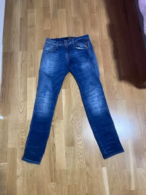 Replay Anbass 30/32 - Säljer ett par blå Replay Anbass jeans med snygg tvätt och klassiska fem fickor. Jeansen har slim passform, normal midja och är tillverkade i mjukt bomullsmaterial med lite stretch. Perfekta för dig som gillar en modern och stilren look.