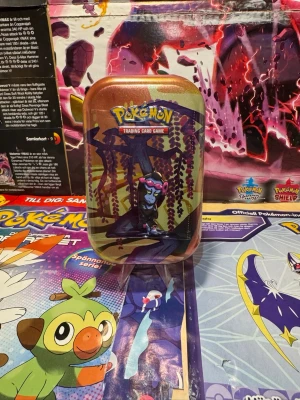 Pokémon TCG: Scarlet & Violet—Shrouded Fable Mini Tin (Munkidori) - Pokémon TCG: Scarlet & Violet—Shrouded Fable Mini Tin (Munkidori) Pokémon-favoriter i din handflata! Ta din samling till nästa nivå med denna exklusiva Mini Tin med den mystiska Pokémon Munkidori. Perfekt storlek för att ta med dina favoritkort överallt! Innehåll i denna Mini Tin: • 2 Pokémon TCG: Scarlet & Violet—Shrouded Fable boosterpaket. • 1 klistermärkesark. • 1 Pokémon-art kort som visar motivet från denna Mini Tin – samla alla 5 i serien för att färdigställa bilden! 