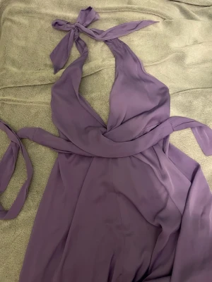 Lila balklänning i satin - Balklänning som går att knyta på många sätt. Använd en gång. Går ner på vaderna på mig som är 165cm.