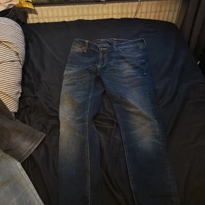 Blå jeans från Nudie Jeans - Säljer ett par snygga blå jeans från Nudie Jeans i bra skick. De har en klassisk femficksdesign och är tillverkade i slitstarkt denim. Perfekta för både vardag och fest! 🕺 köpte dem för 1500 kr nypris och har använt dem en gång men säljer pågrund av fel storlek