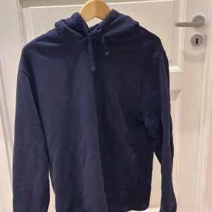 Blå These glory days hoodie - Snygg mörkblå hoodie från These Glory Days i storlek Large. Tröjan har huva med snörning och långa ärmar, perfekt för chill dagar. Materialet är mjukt och känns som bomull, vilket gör den skön att bära. Enkel och stilren design utan tryck eller mönster.