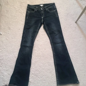 Bootcut jeans från Gina Tricot  - Mörkblå bootcut jeans från Gina Tricot med kontrastsydda sömmar och snygga broderade detaljer på bakfickorna. Low waist använda fåtal gånger