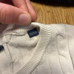 Vit kabelstickad tröja från GANT - Pris kan diskuteras. Vit kabelstickad tröja från GANT med rund hals och diskret logga broderad på bröstet. Tröjan har långärmad passform och ribbade muddar vid hals, ärmslut och nederkant. Perfekt för dig som gillar klassisk och clean stil.