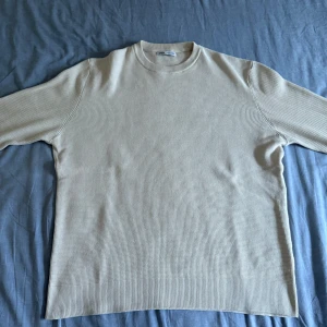 Ribbad Zara Tröja  - Snygg beige långärmad tröja från Zara med ribbad struktur och rund hals. Tröjan har en clean och enkel design, perfekt för dig som gillar stilrena plagg. Materialet är mjukt och skönt, och passformen är normal. Passar dig som vill ha en chill och tidlös look.