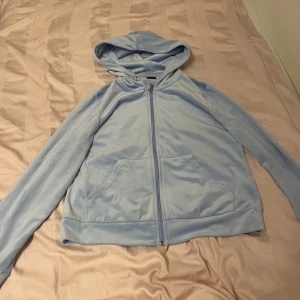 Ljusblå velour hoodie med dragkedja - Mjuk och skön ljusblå hoodie från Gina Tricot i velourmaterial. Tröjan har huva, långa ärmar, fickor framtill och hel dragkedja. Perfekt för chill dagar eller när du vill ha en cozy look.