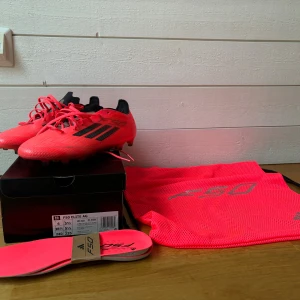 Adidas F50 Elite AG fotbollsskor 38⅔ - Säljer ett par Adidas F50 Elite AG fotbollsskor i en riktigt skarp neonrosa färg med svarta detaljer och snörning. Skorna har platt sula med dobbar för konstgräs och är tillverkade i lätt syntetmaterial. Medföljer originalkartong, extra innersulor och F50-påse. Endast andvända 2 gånger eftersom de inte riktigt passade mig. Pris kan diskuteras!