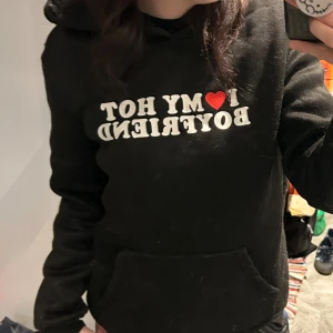 Svart hoodie med tryck - Svart hoodie med tryck. Tröjan har huva, lång ärm och en stor magficka framtill. Storlek S. (Katt finns i hemmet, tvättas innan den postas)