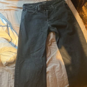 Svarta jeans från Jack & Jones - Svarta jeans från Jack & Jones med klassisk femficksdesign och relaxed passform. Modellen heter Chris och har raka ben, normal midja och storlek 27 30.