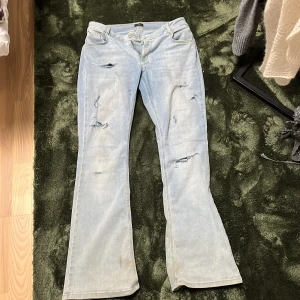 Bootcut ljusblå jeans från NLY Jeans - Snygga ljusblå bootcut jeans från NLY Jeans med egengjorda slitna detaljer och klassisk femficksdesign. Jeansen har gul kontrastsöm och är tillverkade i mjukt denimtyg. Perfekt för dig som gillar en avslappnad och trendig look. Har sytt in dom från början va dom 46 nu ungefär 44