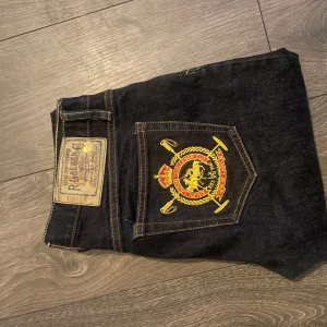Ralph Lauren Thompson 650 jeans, mörkblå - Snygga mörkblå jeans från Ralph Lauren, modell Thompson 650. Klassisk rak passform med gul kontrastsöm och broderad emblem på bakfickan. Tillverkade i bomull med lite elastan för extra komfort. Perfekt för dig som gillar stilrena detaljer.
