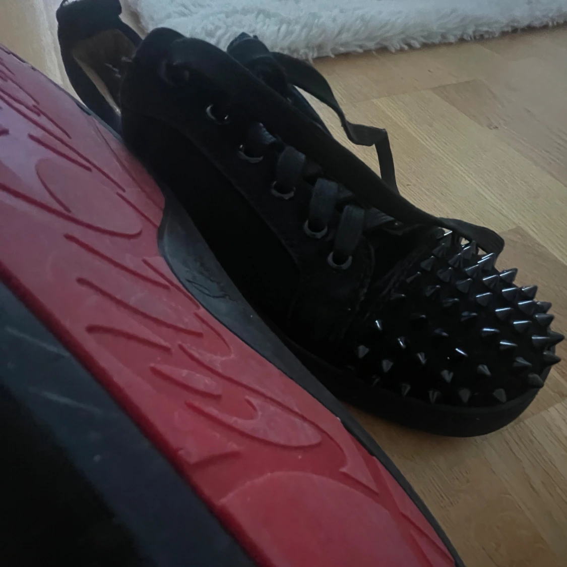 Svarta sneakers med nitar och röd sula