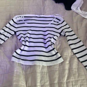 Vit och svart randig ribbad topp H&M - Säljer en vit och svart långärmad topp från H&M i storlek 146/152. Toppen har ett ribbat tyg, raka svarta ränder och en fyrkantig halsringning. Materialet är mjukt och stretchigt, perfekt för en chill och snygg look.