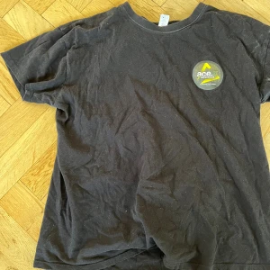 Svart Ace.X Superwhite t-shirt M - Svart t-shirt med rund hals och korta ärmar från Ace.X Superwhite. Stor tryckt logga i gult, vitt och grönt både fram och bak. Materialet är mjuk bomull och passformen är normal. Perfekt för dig som gillar streetwear och grafiska prints. Kan bara få tag på från säljare. Sällsynt