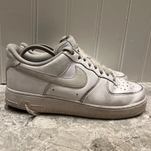 Nike Air Force 1 vita sneakers - Klassiska Nike Air Force 1 sneakers strl 42 men passar för 43. I helvitt skinn med perforerad tå, snörning och låg profil. .Skorna är i ett 6-10 skick och pris kan diskuteras. Skriv till mig om några frågor.