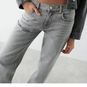 Grå raka jeansbyxor från Ginatricot - Snygga grå jeansbyxor från Ginatricot med rak passform och klassisk femficksdesign. Byxorna har hög midja, knapp och dragkedja framtill samt bälteshällor. Jeansen är tillverkade i bomull och har en cool, ljusgrå tvätt som ger en modern vibe.