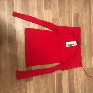 Röd off shoulders tröja - Säljer en snygg röd offshoulder topp från Kappahl i storlek XS. Toppen har långa ärmar och en croppad passform som ger en trendig look. Perfekt för dig som vill sticka ut med en färgstark och stilren topp.