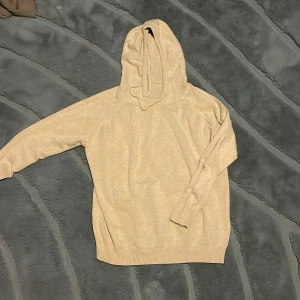 Merino hoodie  - Snygg beige hoodie med huva och snörning. Tröjan har lång ärm och ribbade muddar vid ärmslut och nederkant. Perfekt för en chill och avslappnad stil, lätt att matcha med jeans eller sneakers.