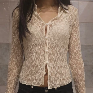 Beige spetsblus med volangärm - ❗️Skriv innan köp❗️Snygg beige spetsblus med transparent spetsmaterial och klassisk krage. Blusen har långa ärmar med volangdetalj vid ärmslut och knappar framtill. Köpt secondhand hos humana och har ingen tagg. Har använt den själv ett fåtal ggr. 