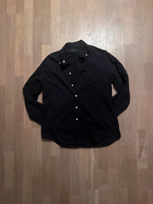 Svart skjorta från Polo Ralph Lauren - Svart långärmad skjorta från Polo Ralph Lauren med klassisk krage och knappar framtill. Skjortan har broderad logga på bröstet och är tillverkad i bomull. Perfekt för dig som gillar stilrena och tidlösa plagg.  Passar för runt 184 🙌  9/10 skick  ✅ Skickar inom 48 timmar om inte samma dag 🚚