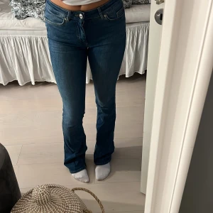 Blå bootcut jeans från Only - Säljer ett par klassiska blå jeans från Only med bootcut-modell och medelhög midja. Jeansen har fem fickor, snygga sömmar och en skön passform som sitter tajt upptill och släpper vid bensluten. Perfekta till sneakers eller boots.