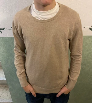 Beige rundhalsad tröja från Riley - Snygg beige tröja från Riley med rund hals och långa ärmar. Tröjan är tillverkad i en mjuk mix av bomull, nylon och silke som gör den skön att ha på sig. Passformen är normal och den neutrala färgen gör den enkel att matcha med jeans eller andra plagg.