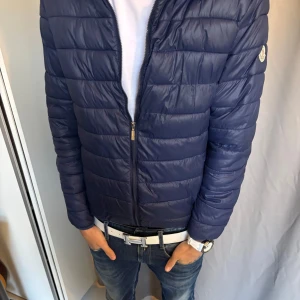 Mörkblå jacka från Moncler - Säljer en mörkblå pufferjacka från Moncler med klassisk quiltad design och dragkedja framtill. Jackan har långärmade ärmar och en snygg ståkrage. Moncler-loggan sitter på vänster ärm. Perfekt för dig som gillar stilren look. Taggen innan för jackan har tyvärr gött bort i tvätten .Passar perfekt nu till hösten/vintern. Hör gärna av er vid frågor🙌🙌