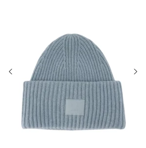 Ljusblå  mössa från Acne Studios - Snygg blå mössa från Acne Studios med ribbad stickning och uppvikt kant. På framsidan sitter Acne Studios klassiska ansiktslogga i matchande blått.  Mössan är tillverkad i mjuk ull och har en clean, modern look som passar perfekt till kalla dagar. Den är väldigt skön och perfekt på vintern! Nypris är ca 1700kr! Den är i mycket bra skick ! Skriv om ni vill ha bilder på den! 