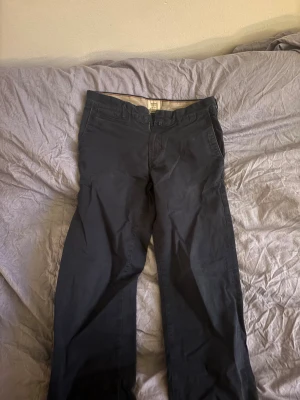 Svarta chinos i bomull - Svarta chinos med klassisk rak passform och diskreta fickor fram och bak. Byxorna är tillverkade i mjuk bomull och har bälteshällor samt dragkedja. Perfekta för en clean och stilren look.