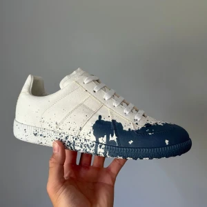 Maison Margiela sneakers med blå färgstänk - Unika sneakers från Maison Margiela i vitt tyg med blå färgstänk och cool splatter-effekt | Nya skor med allt og | Innersula: 26cm | Boxen är lite skadad o hälen super lite böjd  | Använd 1 gång av en kille som sedan returnerade