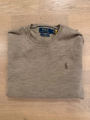 Beige merinoulltröja Ralph Lauren - Snygg beige tröja från Ralph Lauren i tvättbar merinoull. Slim fit-modell med rund hals och broderad logga på bröstet. Sparsamt använd och är fortfarande väldigt len och mjuk. 