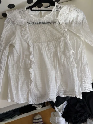 Vit blus med spetsdetaljer - Vit blus från Zara i lätt bomullstyg. Spetsdetaljer över bysten och volanger framtill. Lång ärm och lös passform. Använd ett fåtal gånger, i gott skick utan fläckar eller hål.  Säljs på grund av garderobsrensning.
