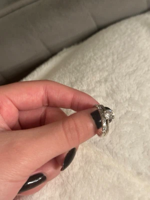 Äkta silver ringar med kristall stenar  - 2 äkta 925 silver ringar. Säljer en stilren silverfärgad ring med en stor klar sten i mitten och matchande tunn ring med små gnistrande stenar runt hela bandet (en av de små stenarna har lossnat).  Perfekt för dig som gillar klassiska smycken med lite extra bling. 