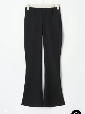 Svarta bootcut kostymbyxor - Säljer ett par svarta kostymbyxor med bootcut passform och hög midja. Byxorna har två knappar framtill, bälteshällor och fickor med lock bak. Materialet är slätt och stretchigt, vilket gör dem riktigt bekväma och snygga.