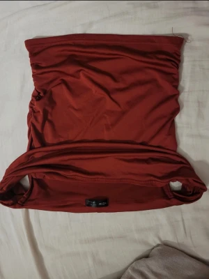 Röd offshoulder-topp från SHEIN - Säljer en röd  topp från SHEIN. Toppen är axelbandslös och har en enkel, tight passform i mjukt och stretchigt syntetmaterial. Perfekt att styla med höga jeans eller kjol för en trendig look.