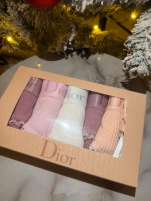 Fem färgglada stringtrosor från Dior - Säljer ett 5-pack stringtrosor från Dior i olika pastellfärger: ljusrosa, vit, lila, persika och gammelrosa. Trosorna är ribbade med bred satinresår där Dior-loggan syns tydligt. Söt spetskant runt benen. Material: 95% bomull, 5% elastan.