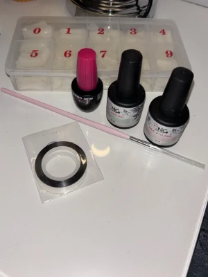 Nagelkit - Nagelkit med två NG gelpolish i färgerna Peach (ljusrosa) och Turquoise (turkos), samt en Base One primer, en tunn rosa pensel, dekorationsband och en låda med lösnaglar. Allt nästan som nytt. Ordinariepris för gelpolish: 125kr/styck