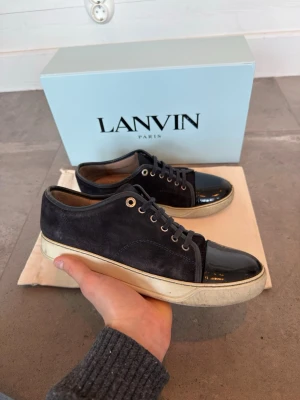 Mörkblå Lanvin skor - Säljer mina mörkblå Lanvin skor med glansig captoe. Skorna är i storlek 41, men passar även 41,5. Skicket är mycket bra (8/10). Box och dustbag ingår. Skriv för fler bilder eller ifall du har några generella frågor!