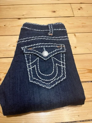 True religon  jeans - äldre vintage - made in Usa, storlek 27 - Ett par supersnygga äldre vintage true religion med tjocka vita sömmar som gör de unika. Troligen från mitten av 2000 talet och jeans som dessa säljs inte längre. Dessa är i strl 27 och låg/mellan midjadeDe är i toppskick och varken slitningar eller liknande.  Mått:  Ytterbenslängd: 96 cm  Innerbenslängd 75 cm  Midja 34 cm  Bara höra av dig om du har frågor eller funderingar angående mått eller fler bilder t.ex.  📦 Skickar inom 24 h, ofta snabbare!