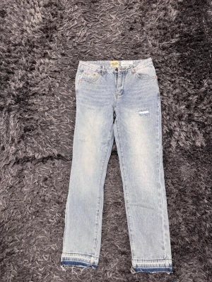  Gallery Dept jean - Säljer ett par ljusblå jeans från Gallery Dept. med klassisk femficksdesign och hög midja. Jeansen har raka ben, slitna detaljer vid knä och råa, fransiga benslut för en avslappnad vibe. Tillverkade i bomull med snygg vintage tvätt och diskreta kontrastsömmar.