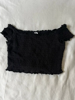 Svart offshoulder croppad topp - Svart croppad offshoulder-topp. Vågigt tyg🥰 perfekt under sommaren 