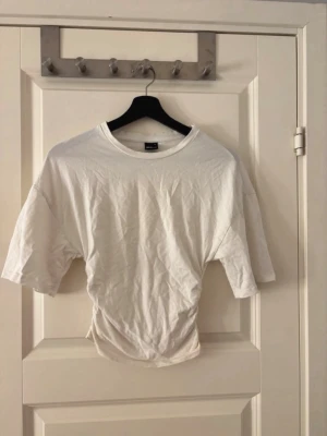 Vit croppad t-shirt från Gina Tricot - Vit t shirt från Gina tricot som nästan aldrig är använd. Den är ”ribbad” på sidan och gör att tröjan sitter tajt och är lite kortare än en vanlig t shirt. Storlek XS