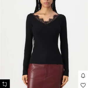Svart ribbad topp med spets - Snygg svart långärmad topp med ribbad struktur och v-ringning dekorerad med spetsdetalj. Modellen är figurnära och har en elegant, feminin look som passar perfekt till både jeans och kjol. Perfekt för dig som gillar stilrena plagg med en twist.